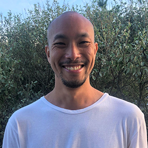 headshot of Bard philosophy professor Yarran Hominh standing outside with shrubbery in the background.