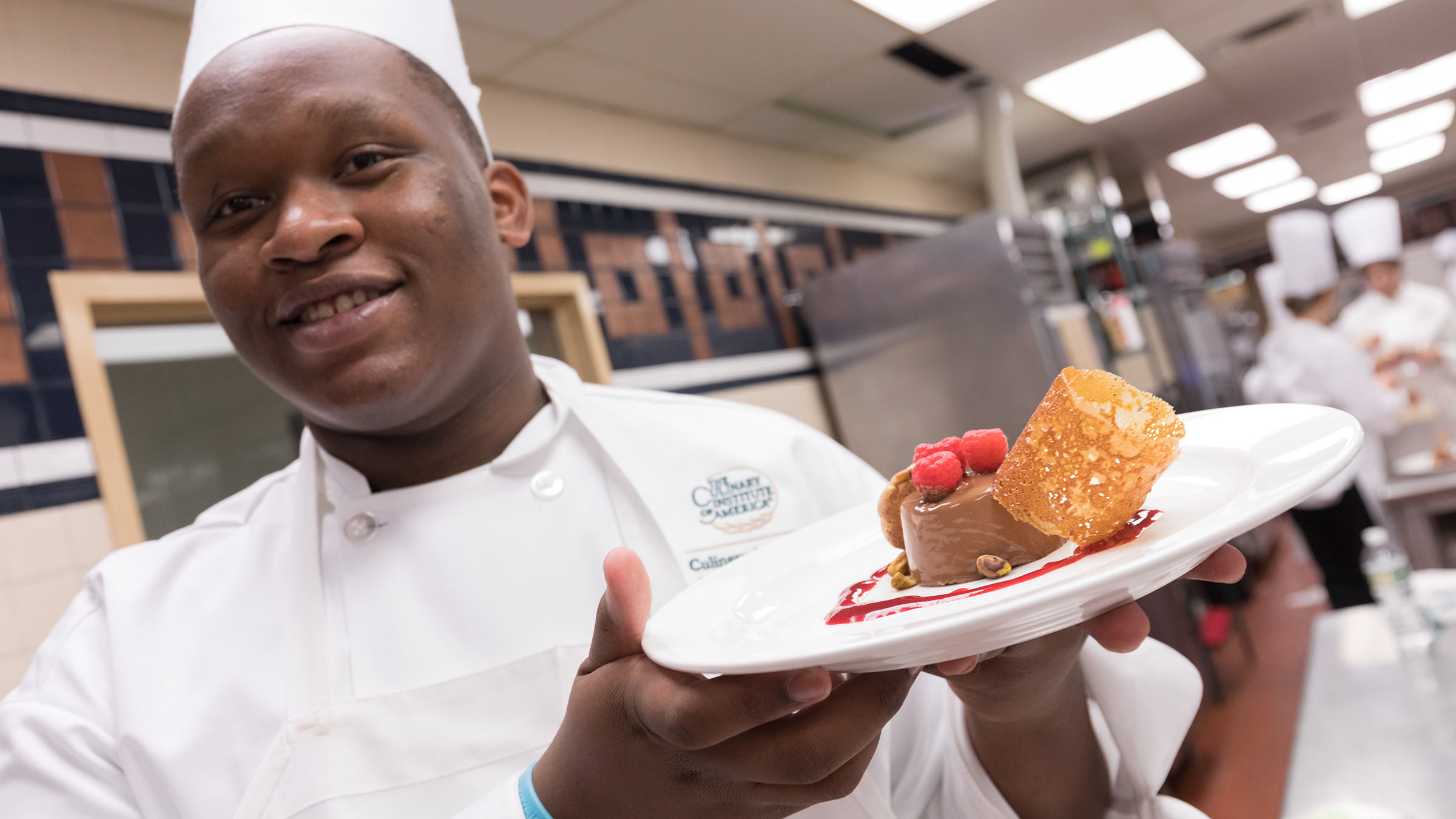 Student chef holding plate of dessert