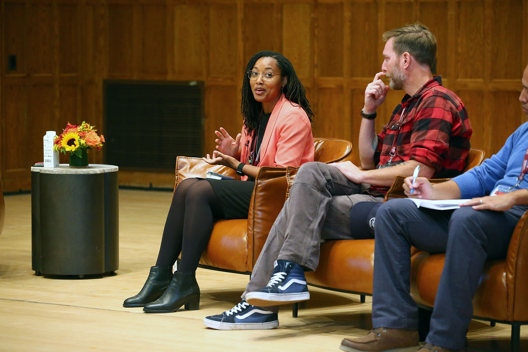 Three people sitting in chairs on a stage speaking.