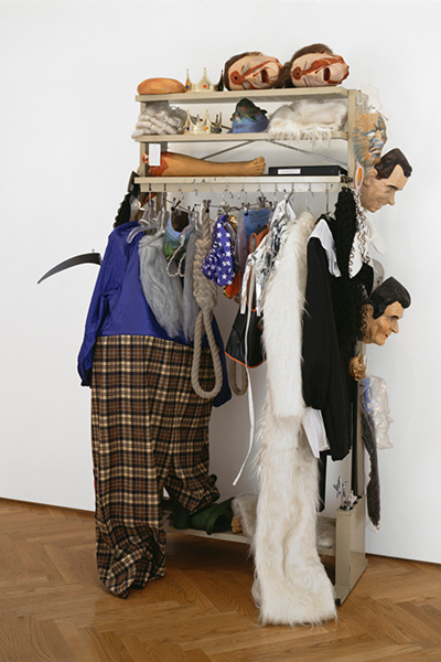 an art installation featuring a clothing rack hung with garments, masks and wigs.