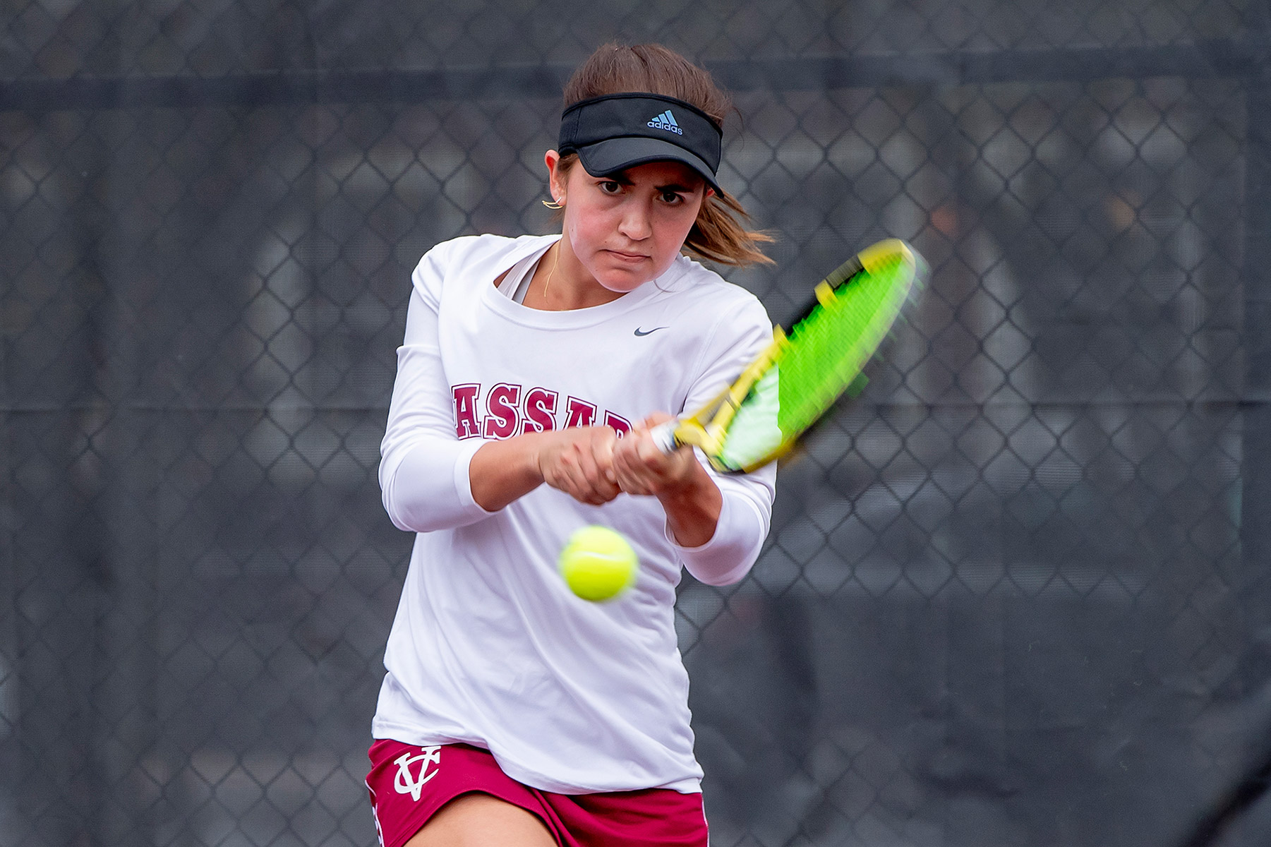 Pictured: Macey Dowd ’25 - Woman hitting a two-handed backhand on a tennis court.