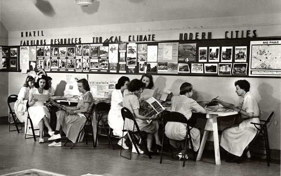 Old black and white photo of women sitting at table studying