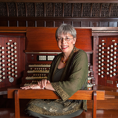 Photo of a woman looking back from the church organ she is sitting in front of