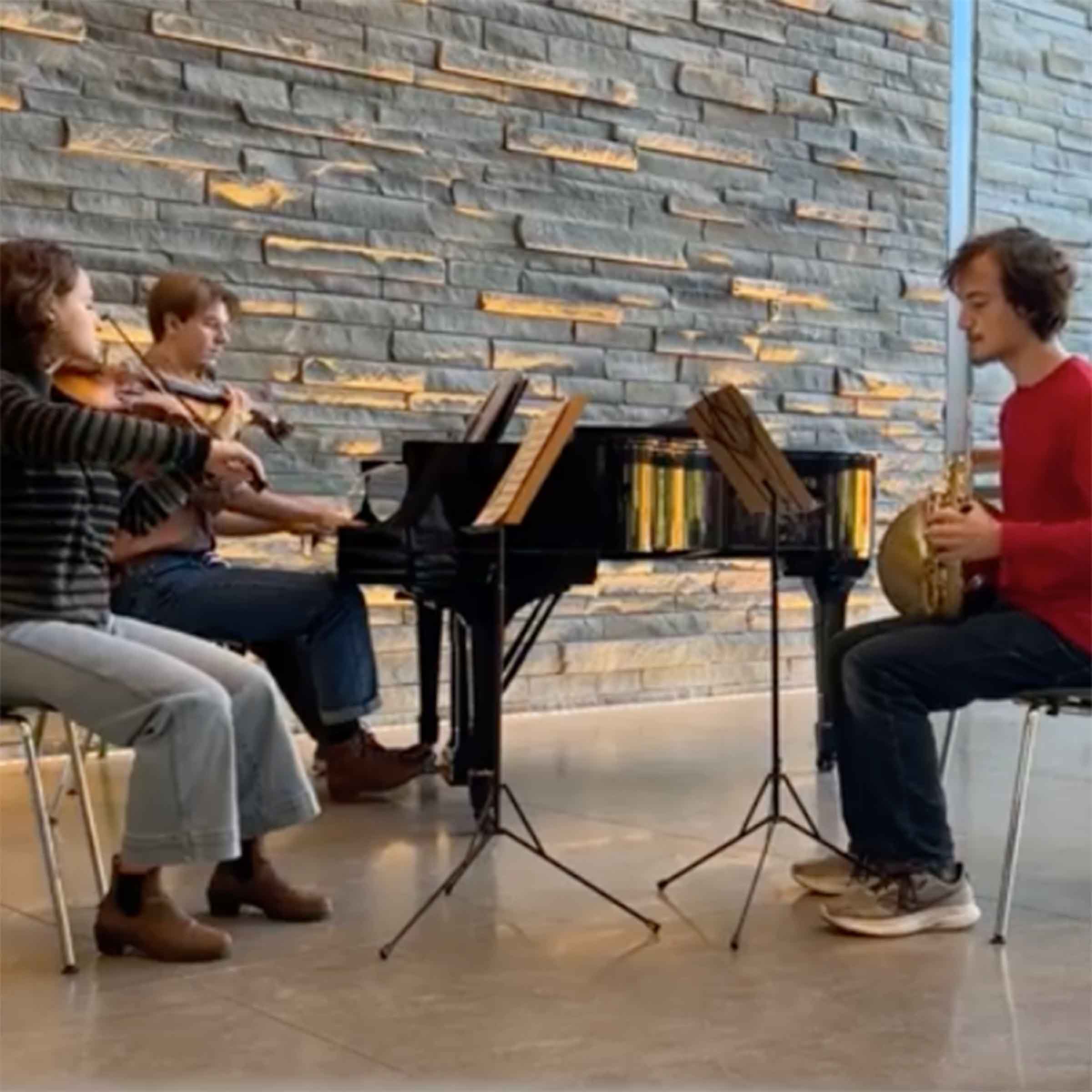 Three musicians playing piano, violin and a horn