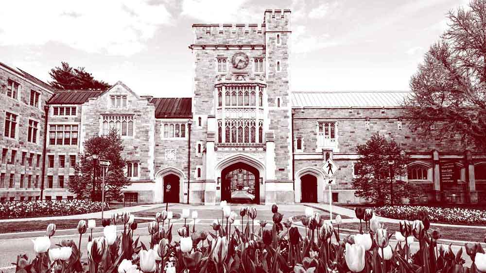 A monochrome photo of the front of the Taylor Hall Gate: a large stone building with the entrance to campus