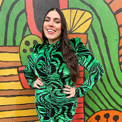 Alyssa Maldonado-Estrada stands in front of a colorful wall mural.