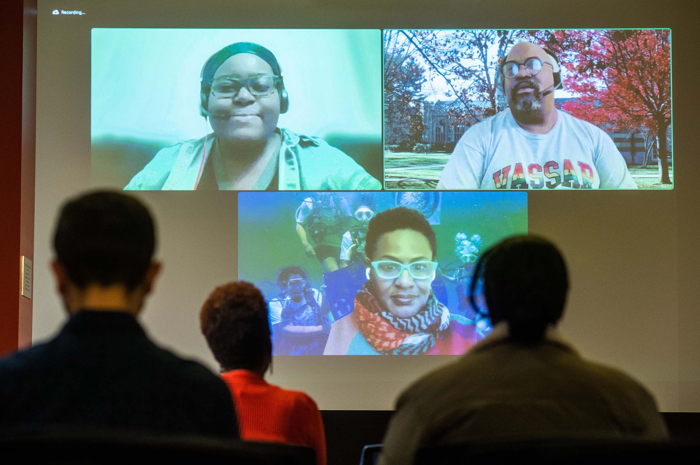 People sitting and watching an online STEM panel projected onto a screen