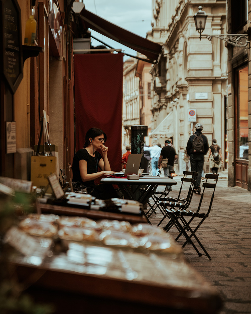 A person sitting at a cafe table in Bologna