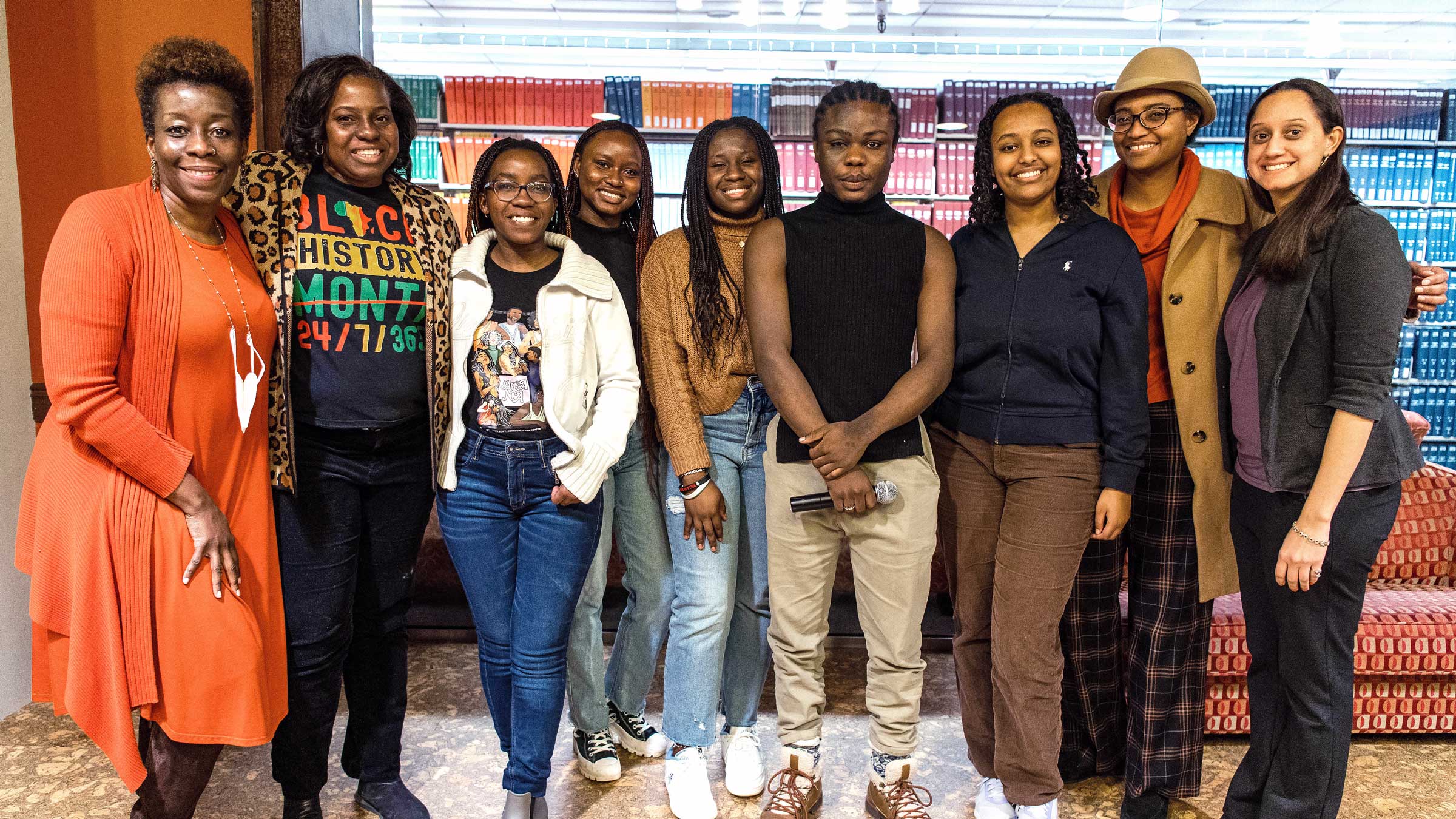 Group shot of nine people standing side by side smiling