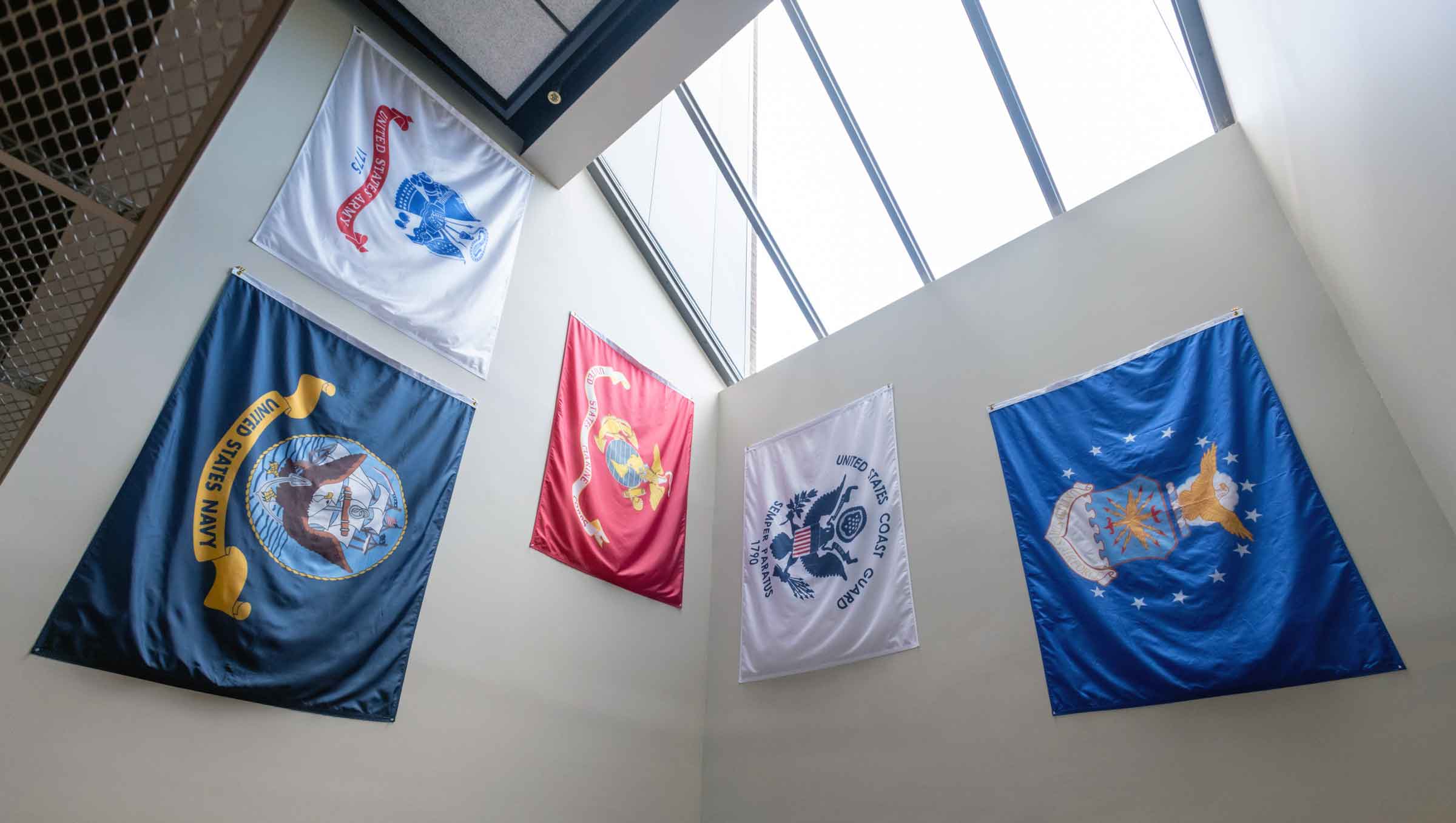 Banners of the U.S. Army, Navy, Marine Corps, Coast Guard and Air Force hanging on a wall
