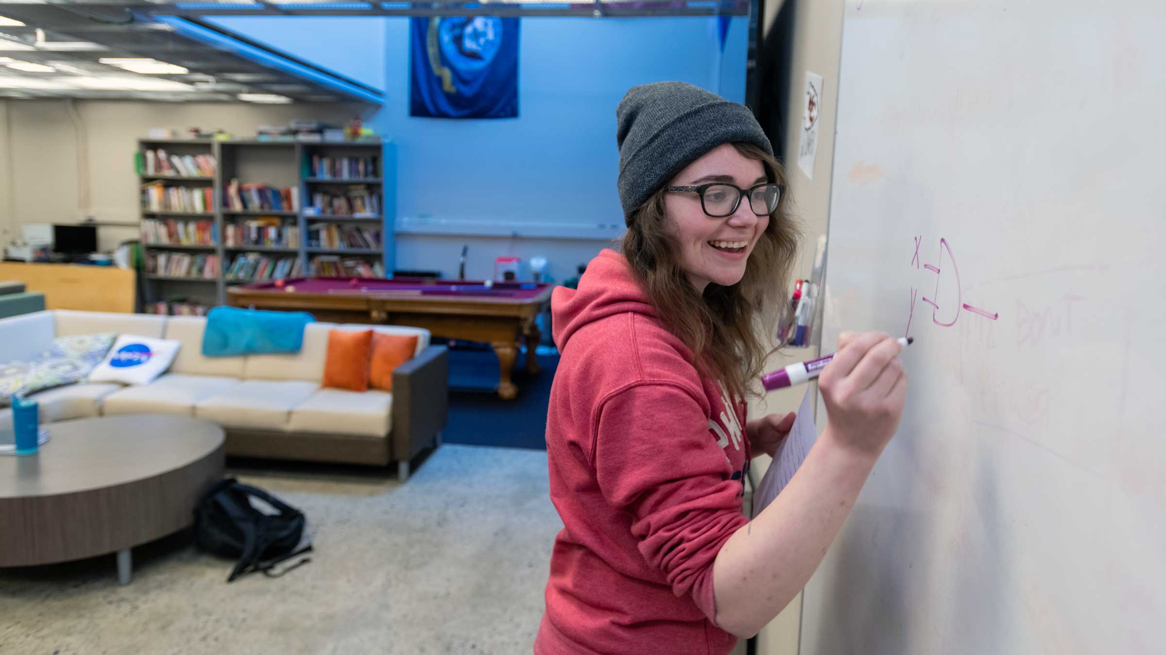 person standing at a white board writing and smiling