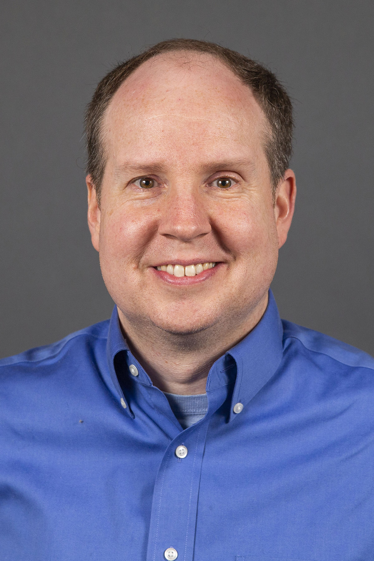 Man in blue collared shirt smiling - Pictured: Brian Daly