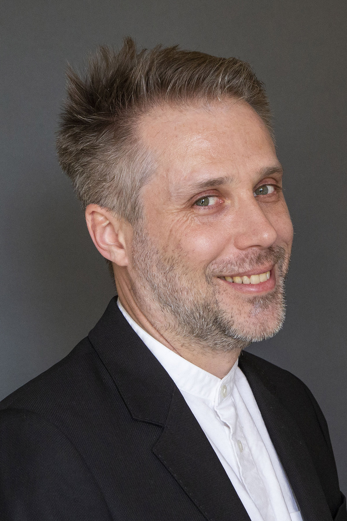 Man smiling with a white dress shirt and black blazer