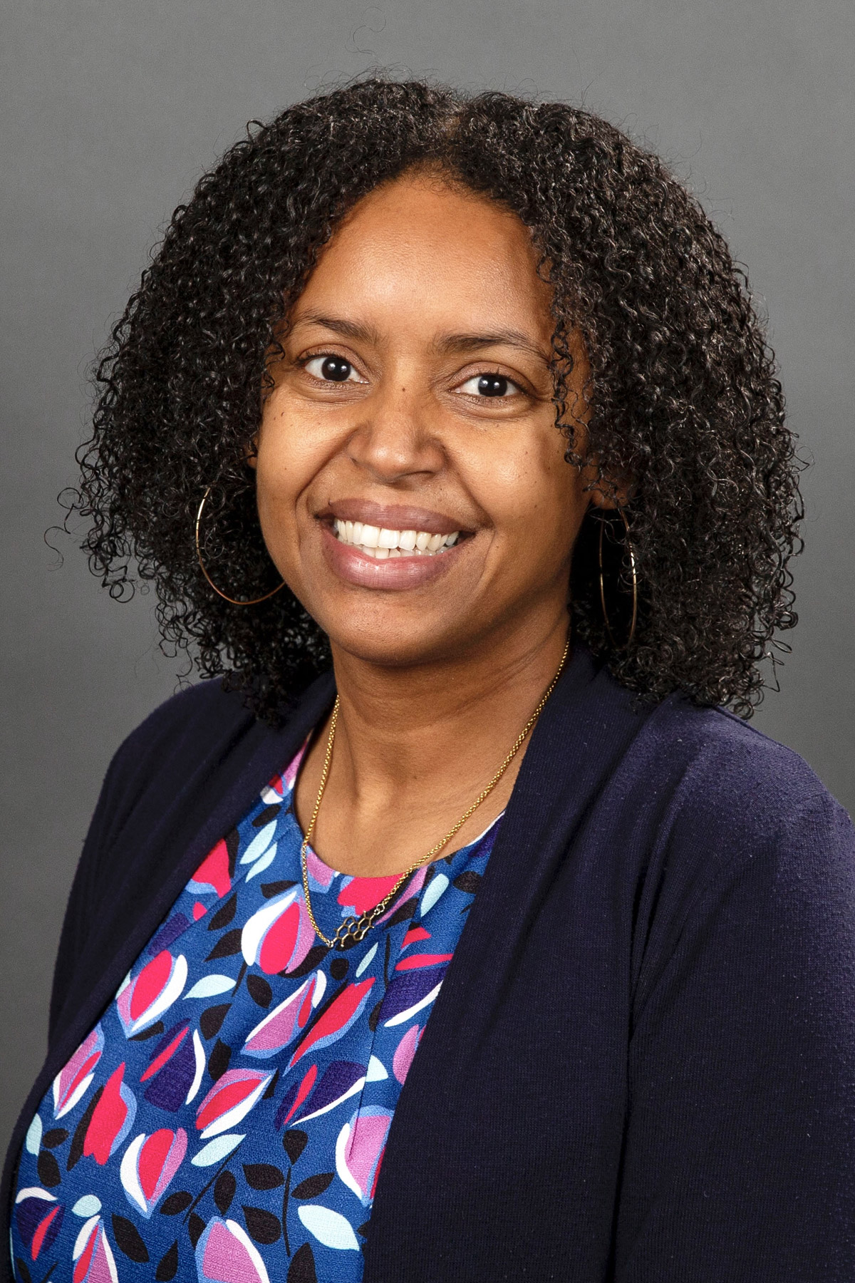 Woman with a blue petal pattern shirt and blue blazer smiling - Pictured: Krystle McLaughlin