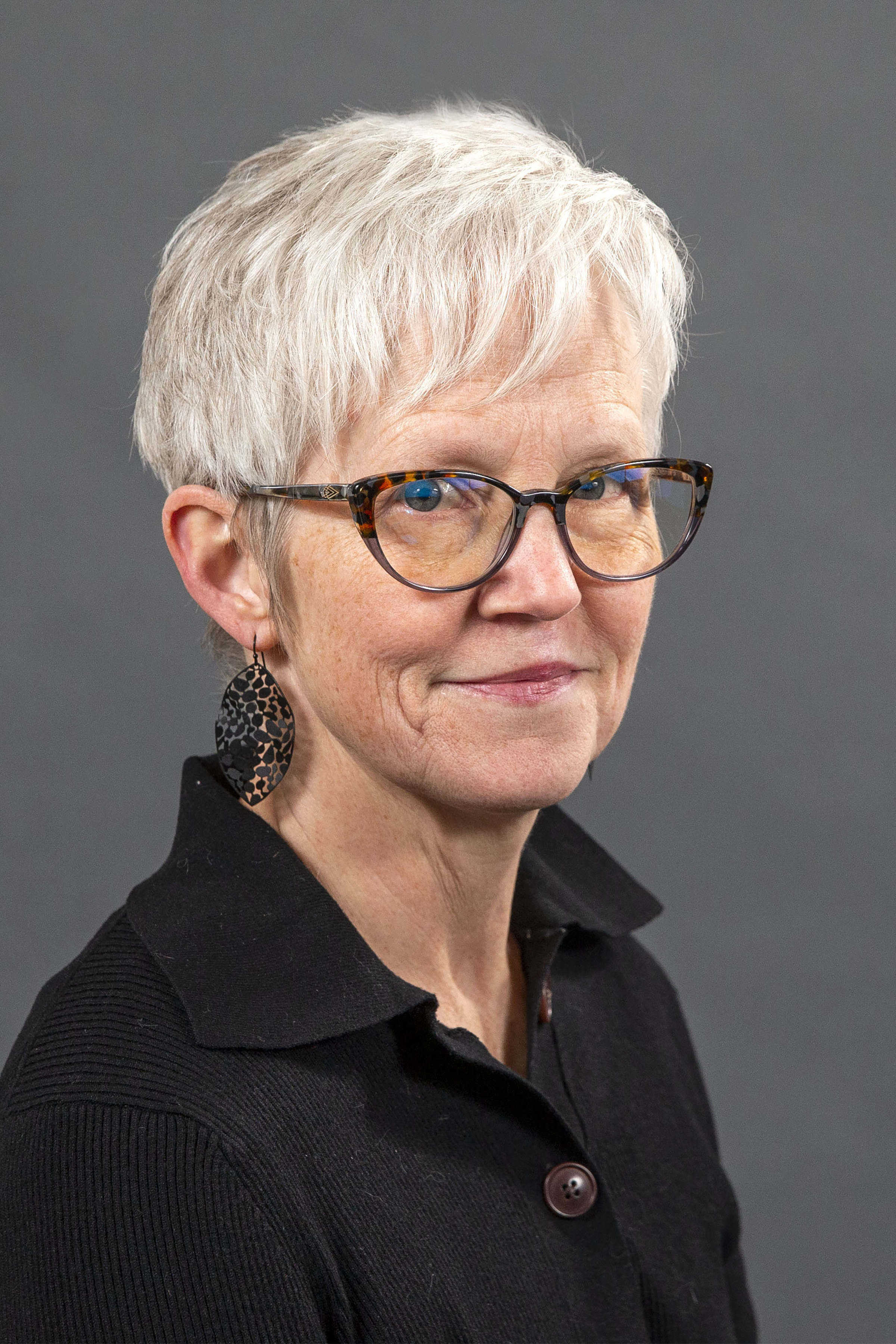 Woman with glasses, black shirt, and grey hair