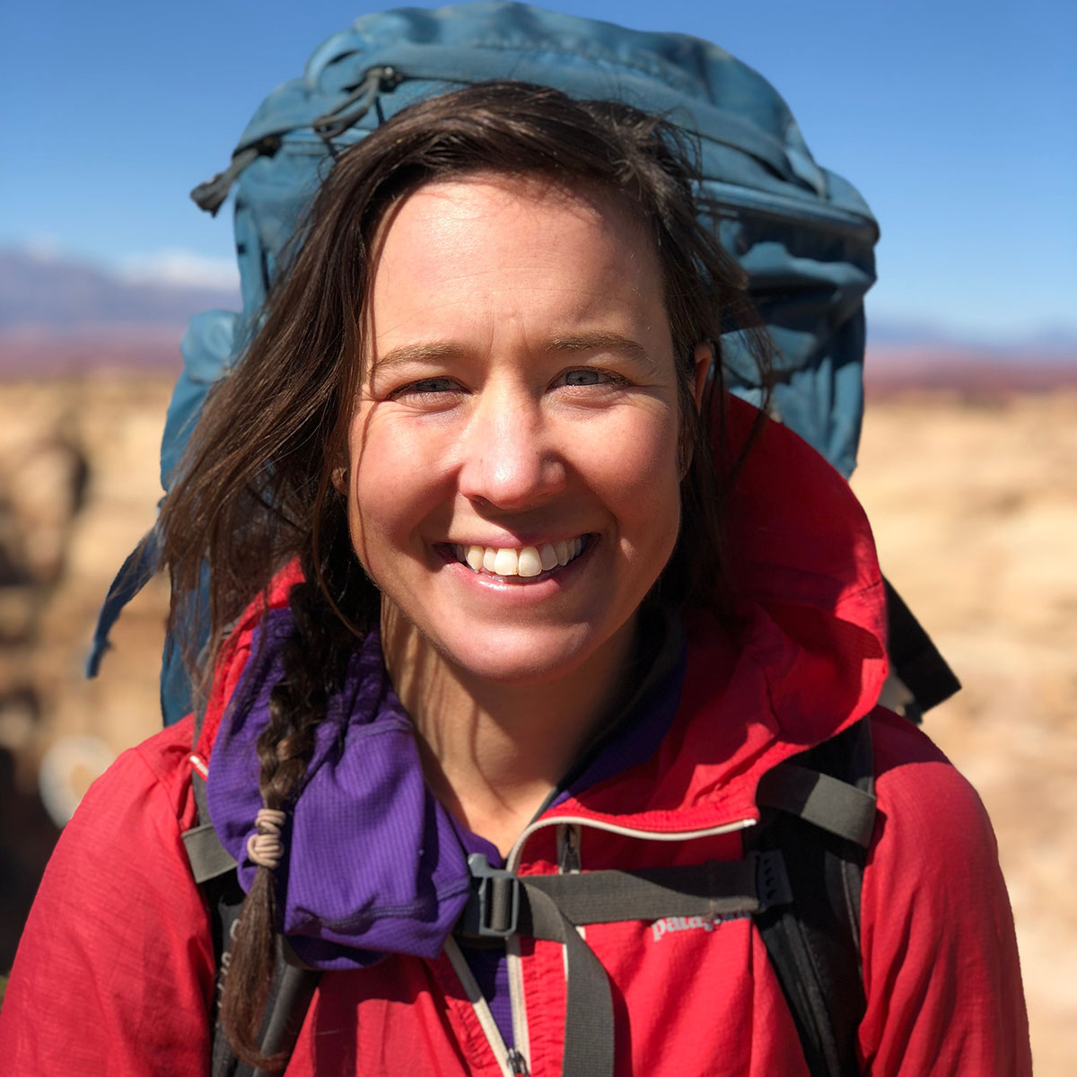 Caroline Goodman wearing a red jacket and green backpack.