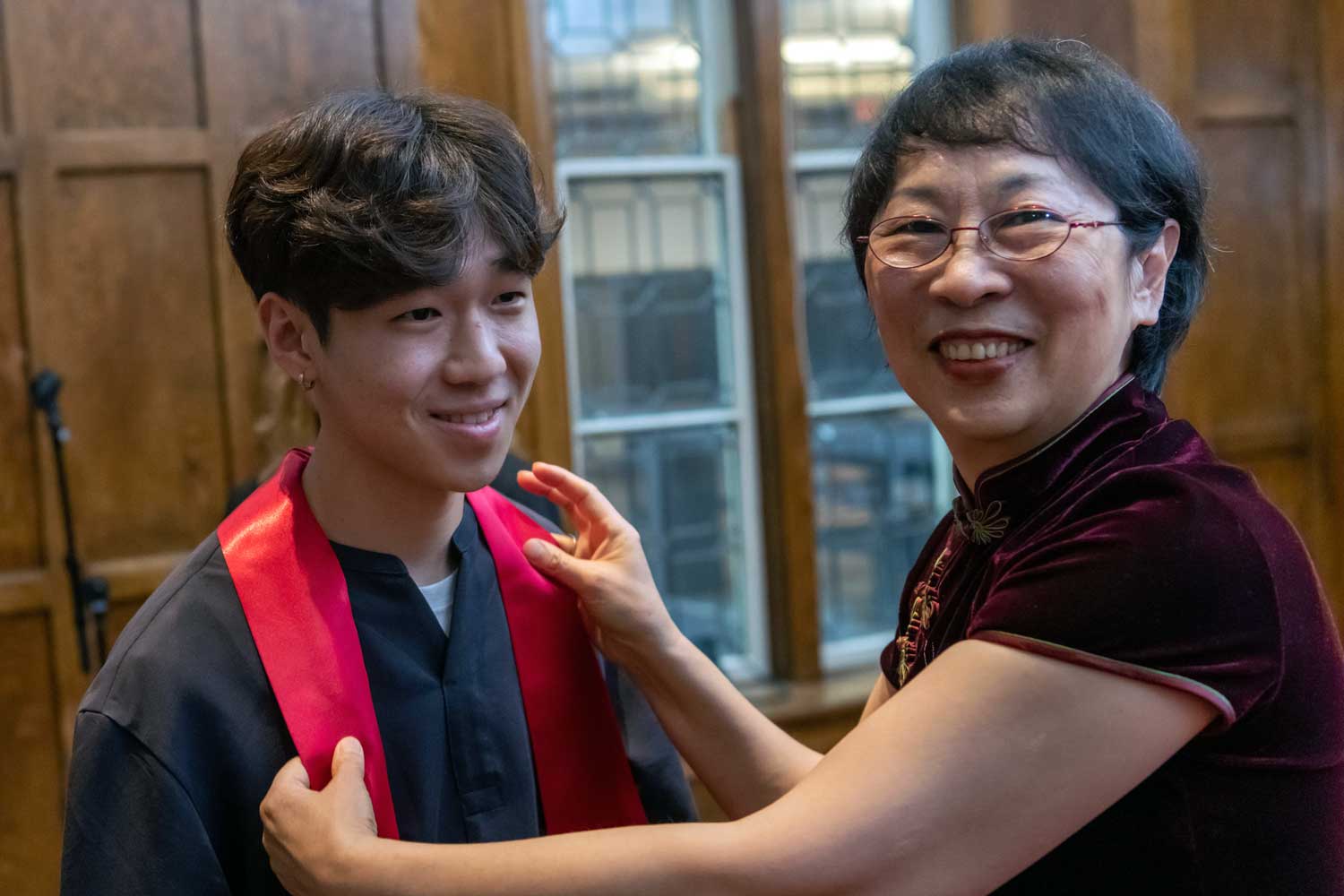 smiling ceremony attendee receive a red satin stole from a presenter