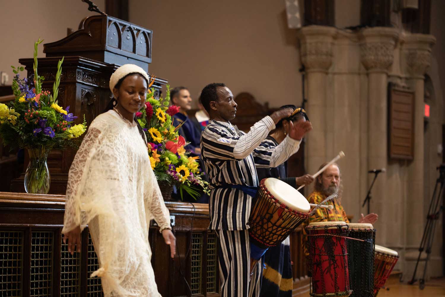 A dancer and two drummers performing