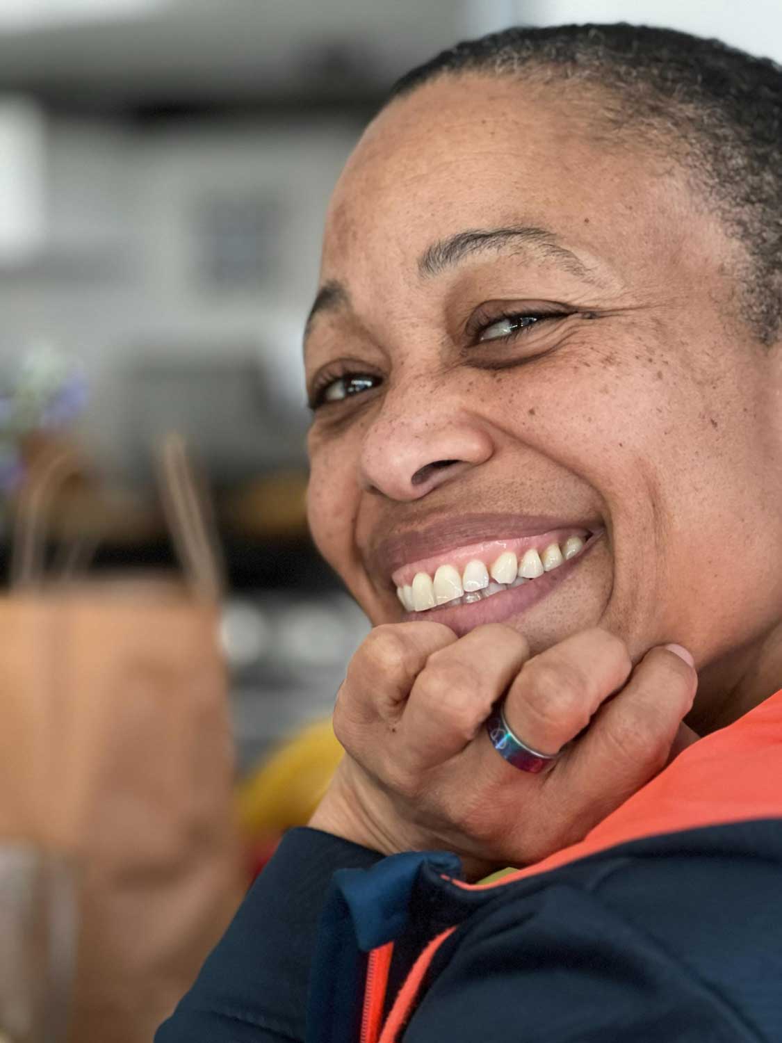 headshot of a person smiling while resting their chin in their hand