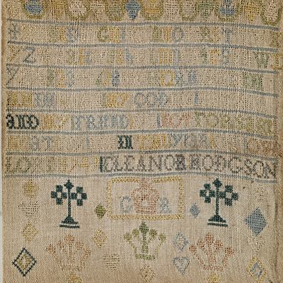 An off-white square of fabric embroidered with colored threads forming the alphabet, the maker's name, and assorted crown imagery.