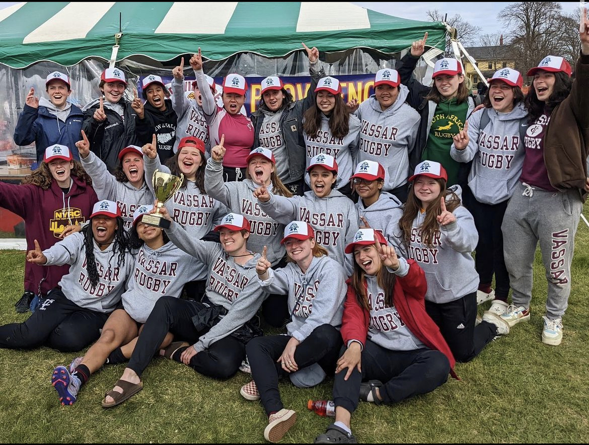 Outdoor group photo of the women's rugby team holding up their winning trophy
