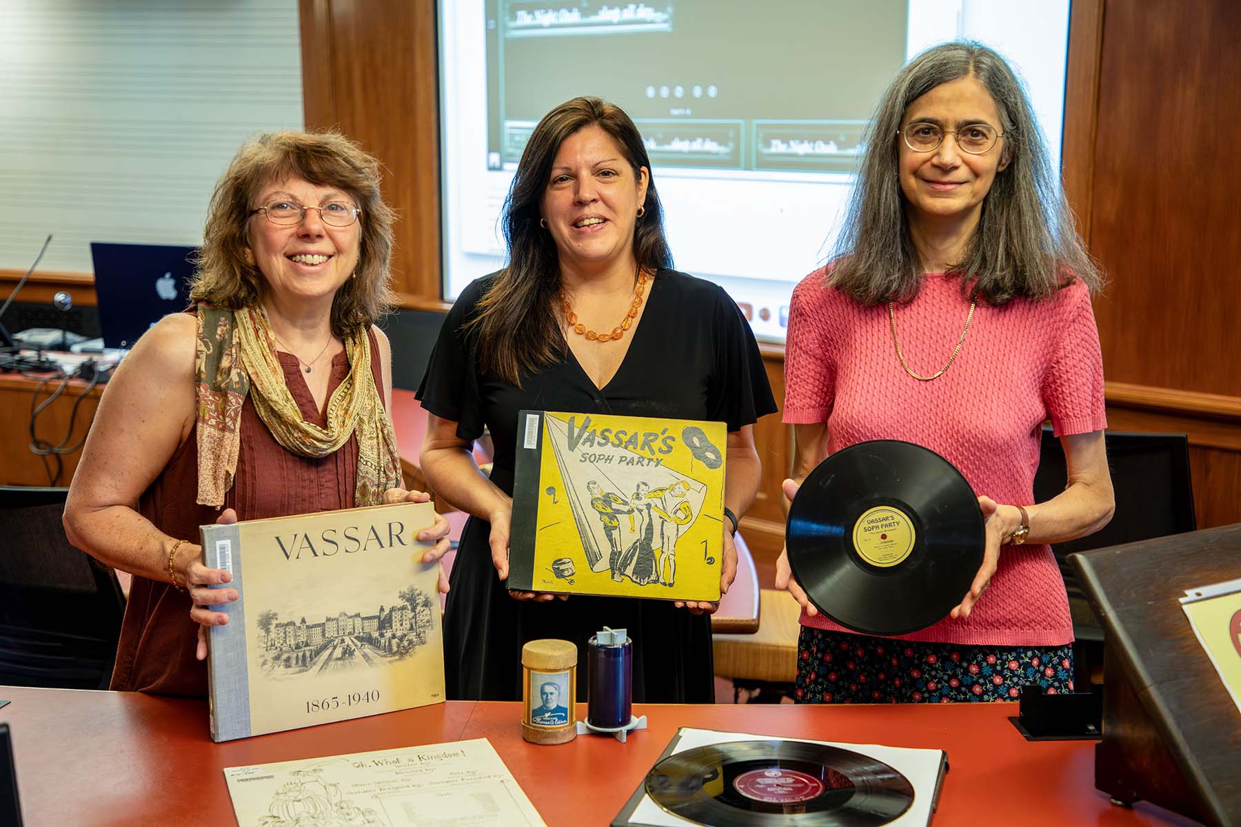Three women, one holding a record, the other two holding old record album books 