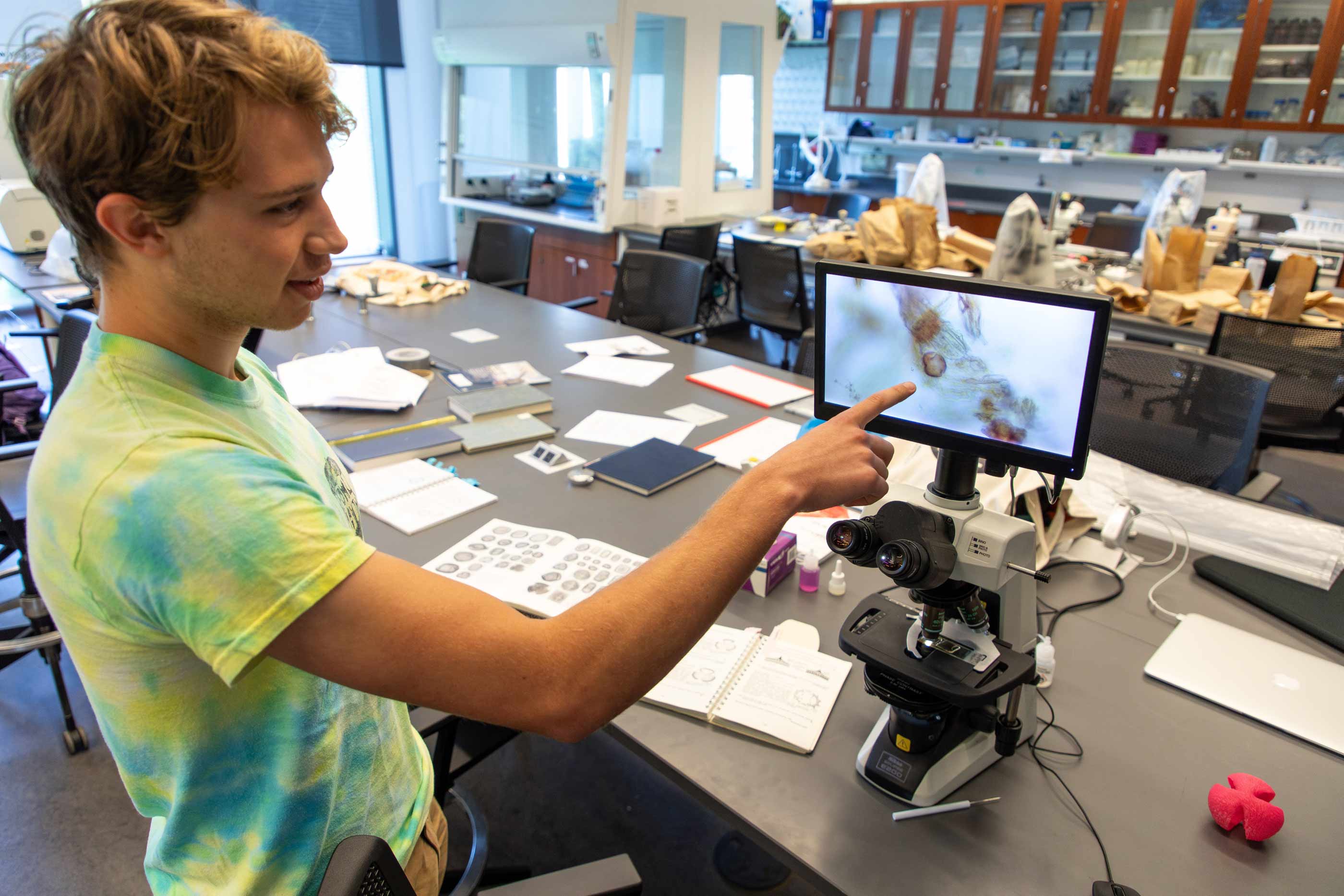 Ezra Potts ’25 points to a screen  showing what pollen looks like when viewed under a microscope.