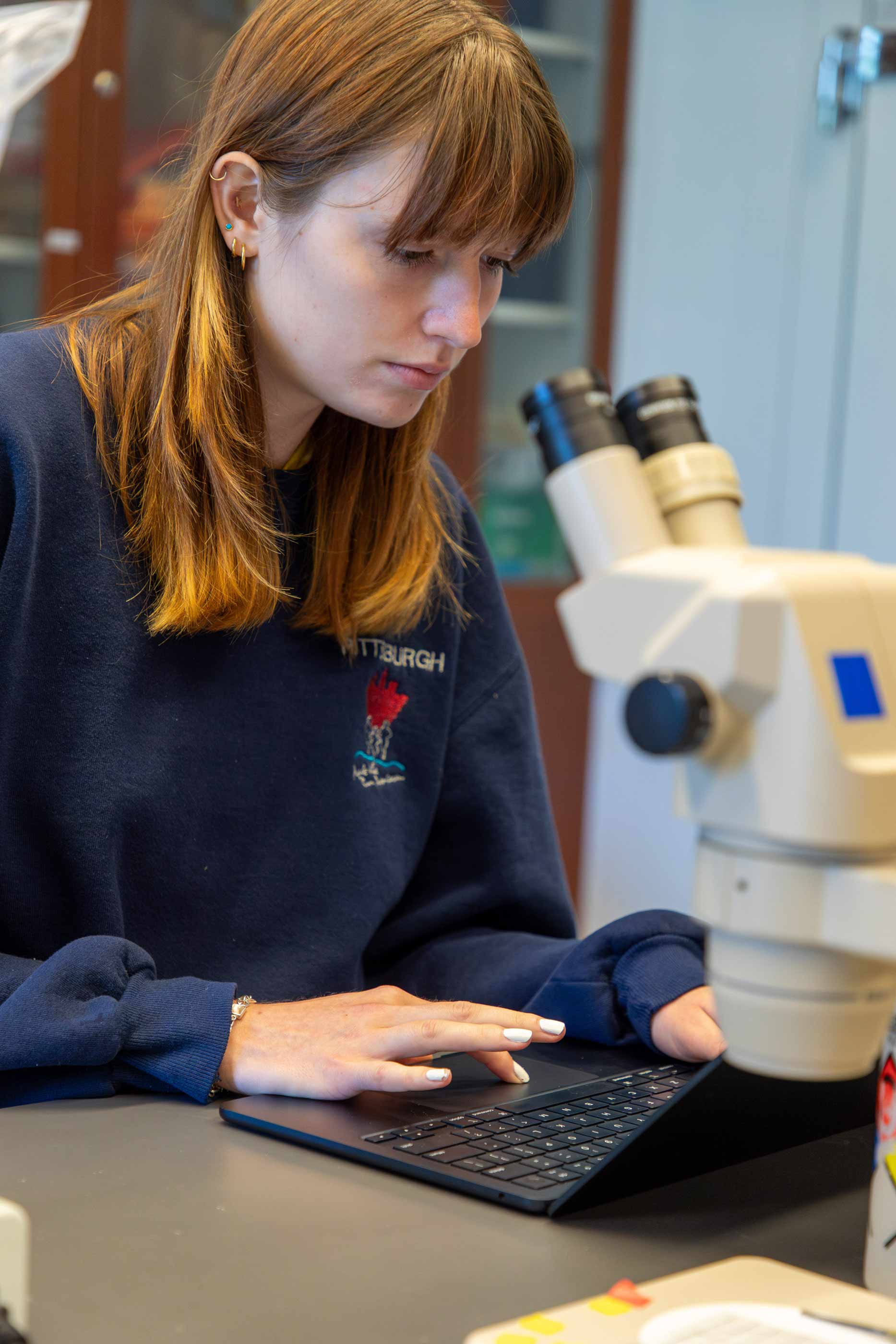 Ava Casalino ’24 viewing a slide through a microscope.