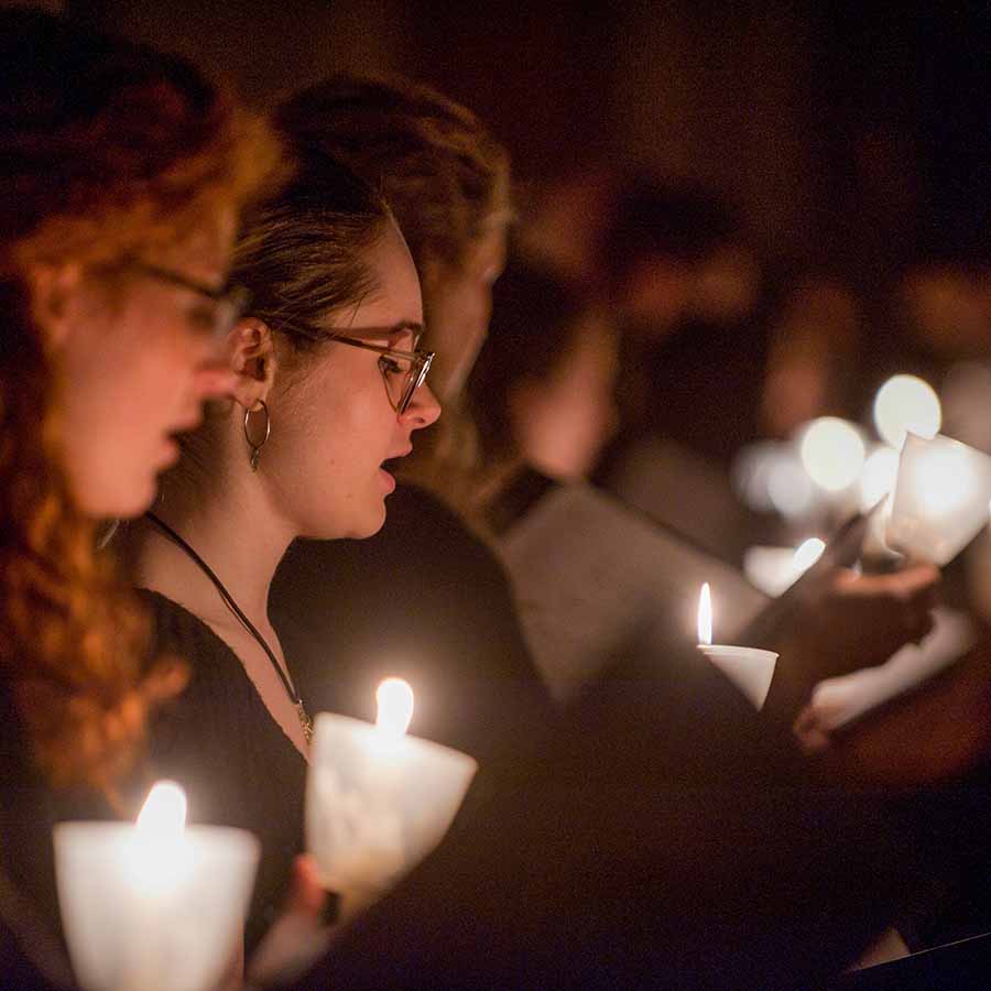 Women in a choir in a dark room holding candles