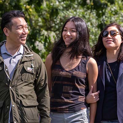 A student and two parents walking on the campus during Families Weekend.