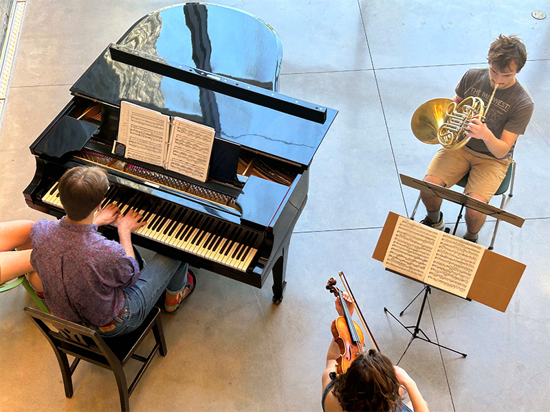 An overhead view of three musicians playing instruments in the Bridge Building.