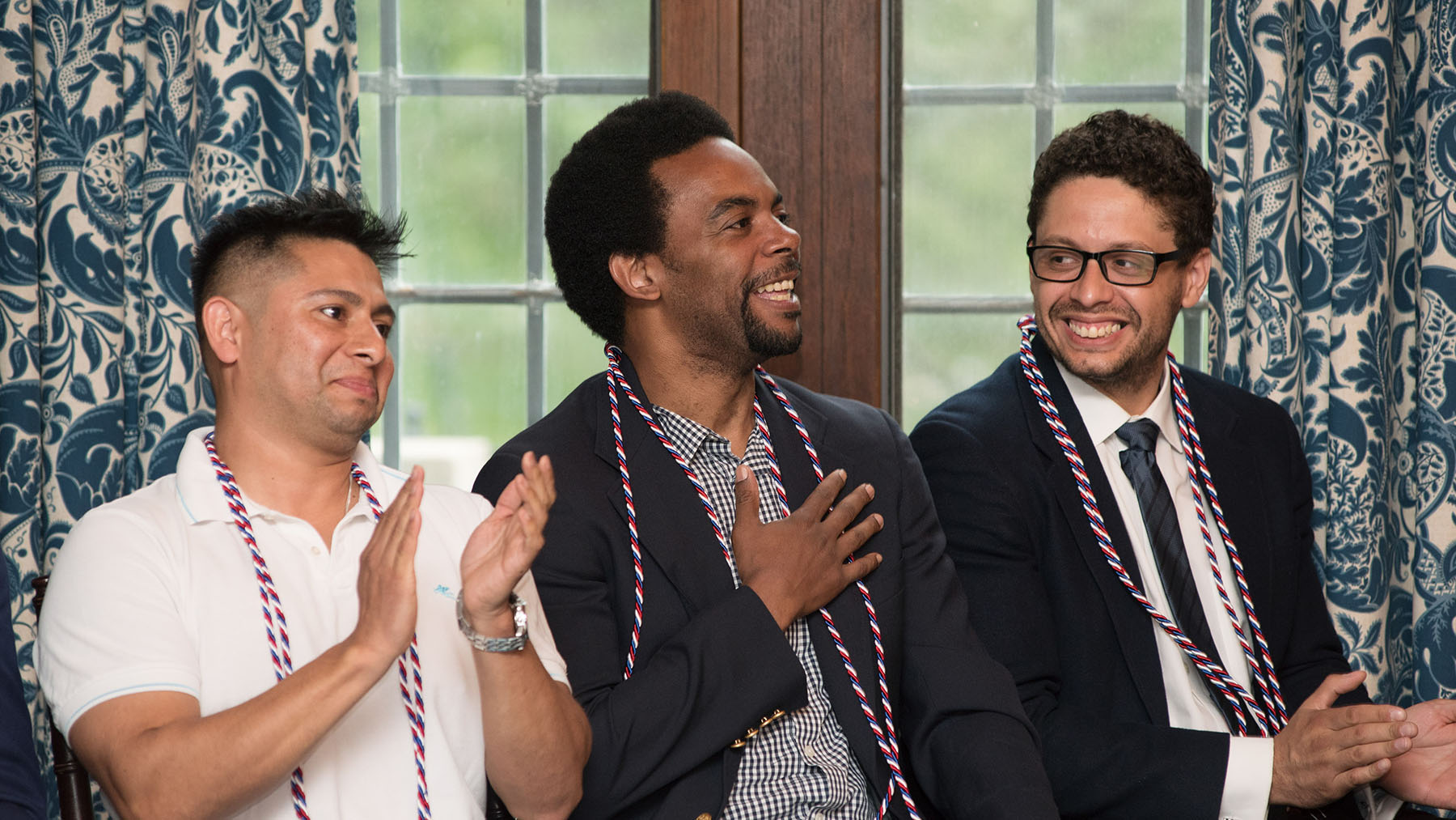 Three people sitting in front of a window smiling and clapping.