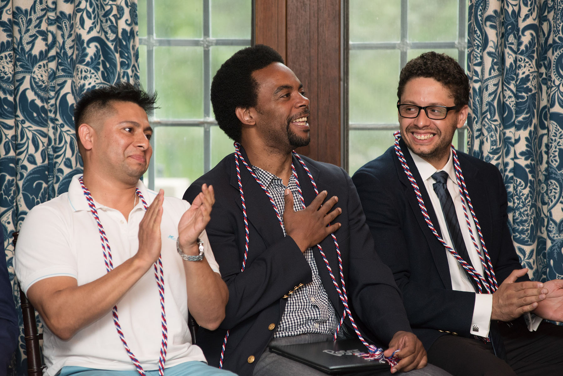 Three people sitting in front of a window smiling and clapping.