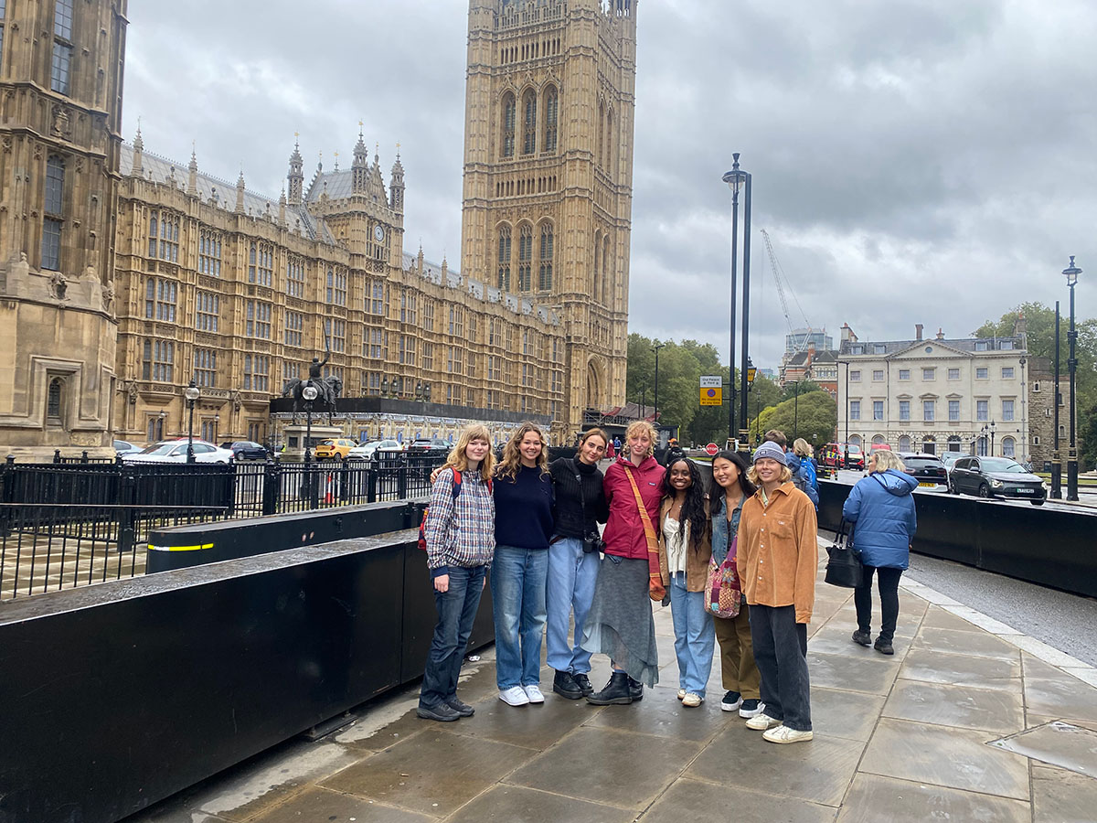 Group of people standing in front of the Palace of Westminster in London.