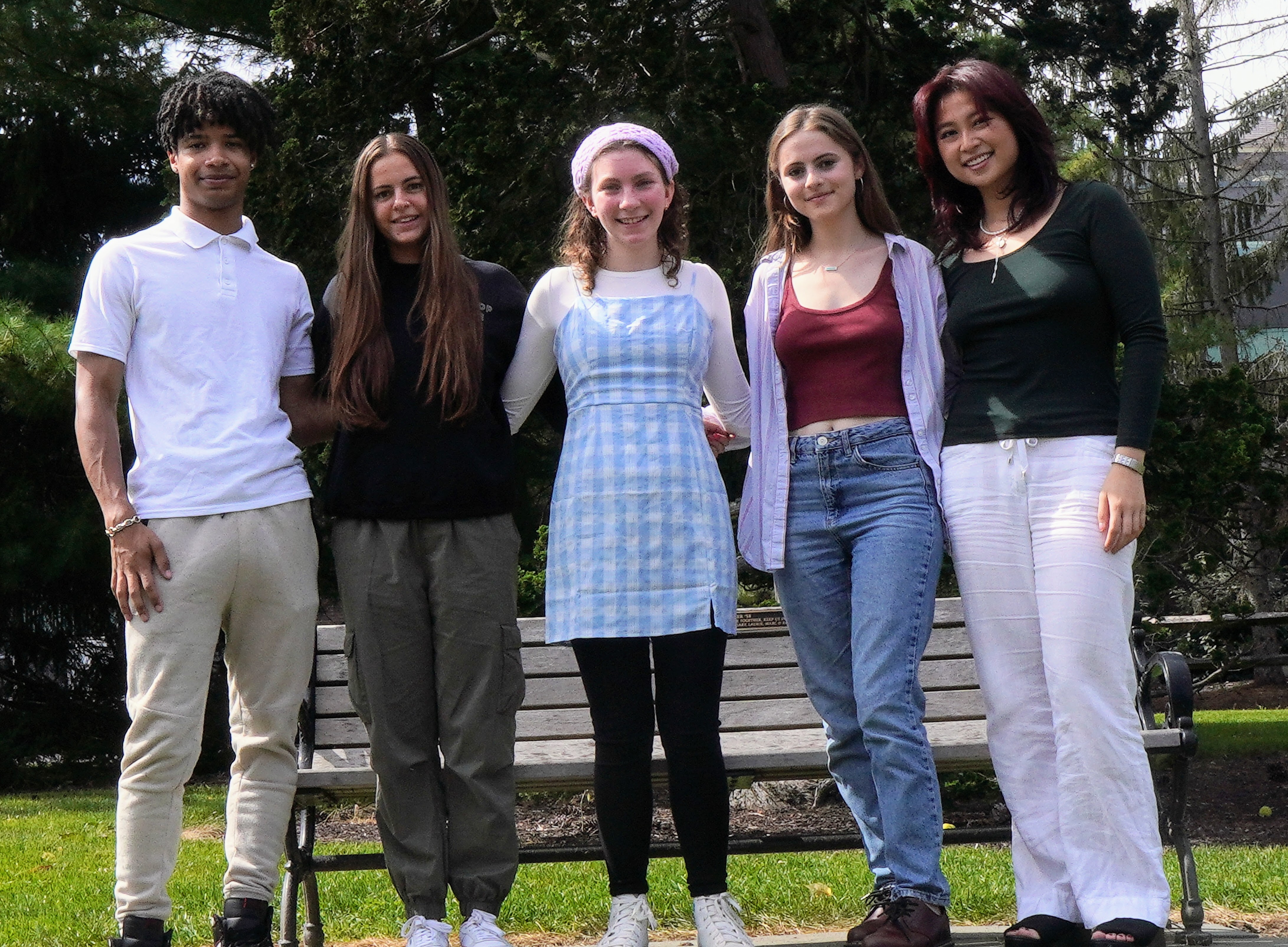 Five students standing outside in front of trees with their arms around each other smiling for the camera.