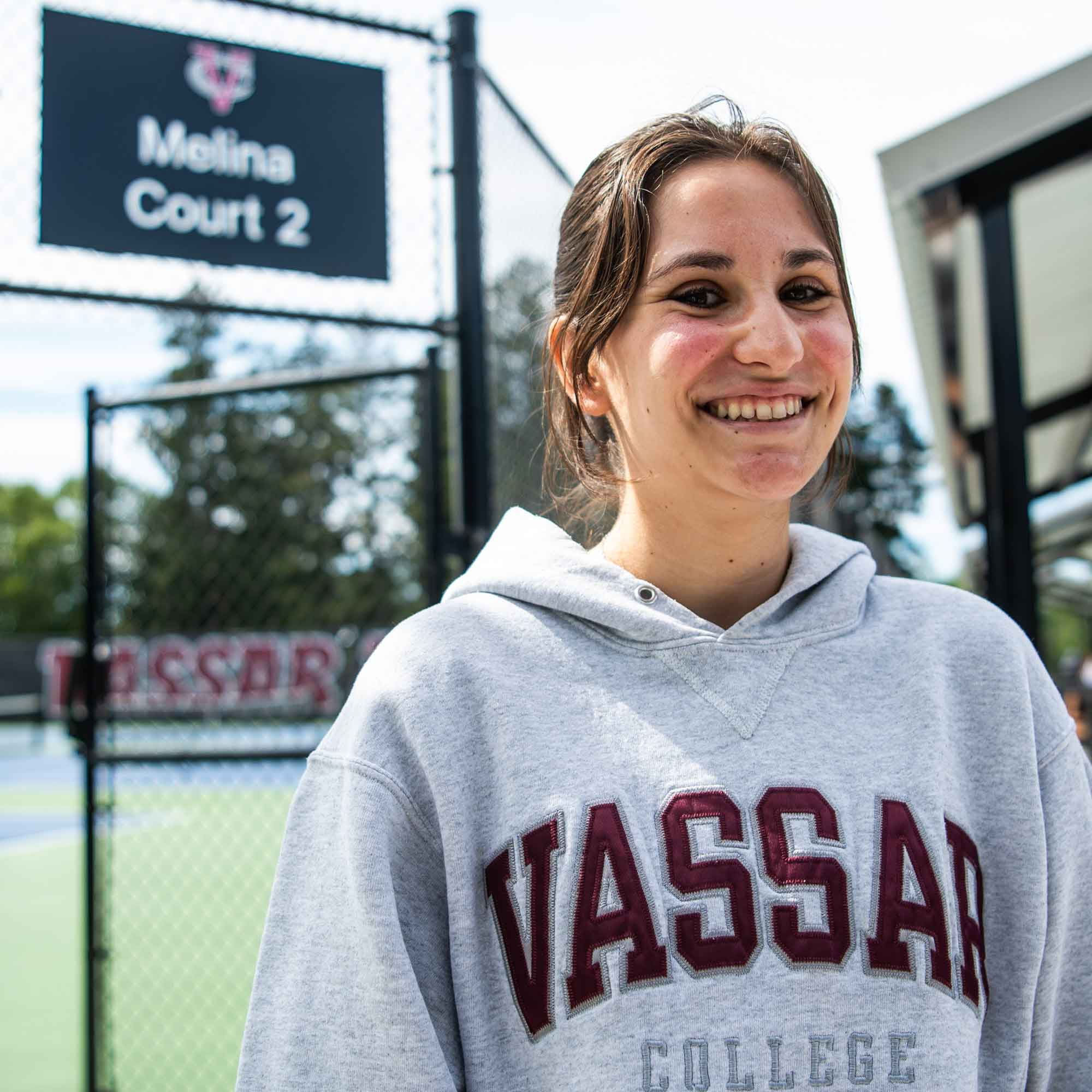 Person standing in front of Melina Court 2 smiling and wearing a Vassar College hooded sweatshirt