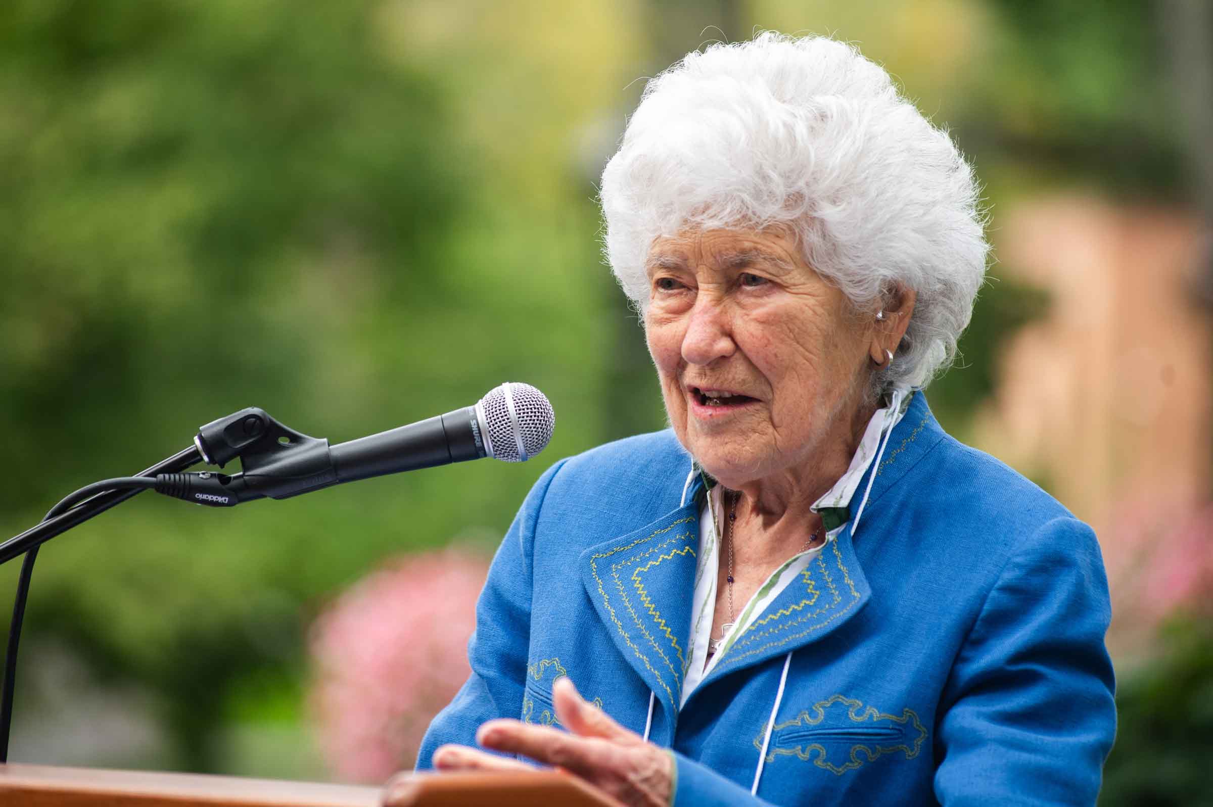 person outside speaking into a microphone behind a lectern