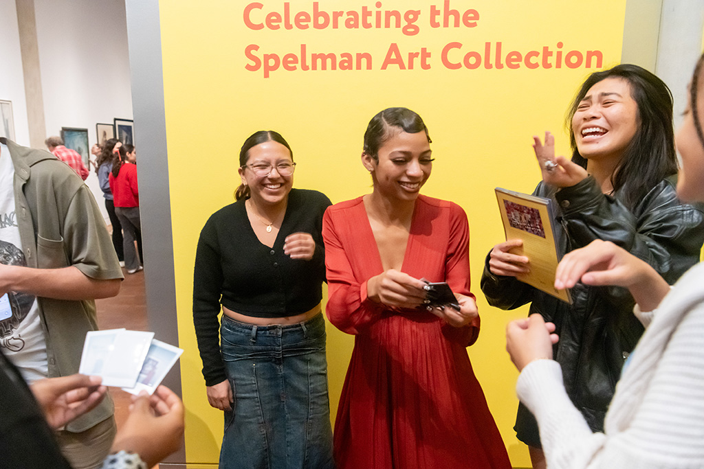 People smiling in front of a yellow wall at the opening of the exhibition.