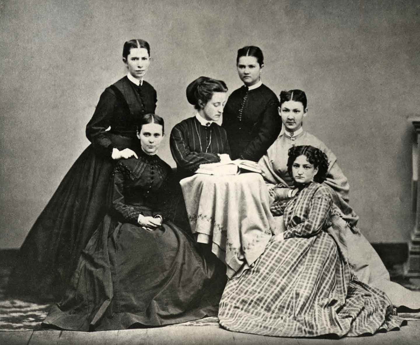 A black and white 19th-century photo of several young people wearing formal dresses.