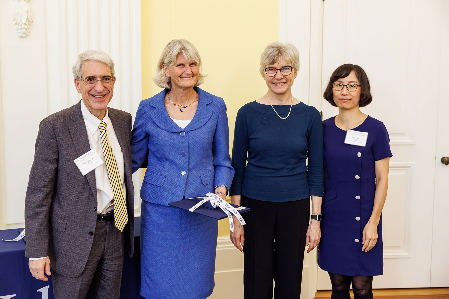 Four people standing side-by-side in a brightly lit room smiling for the camera.