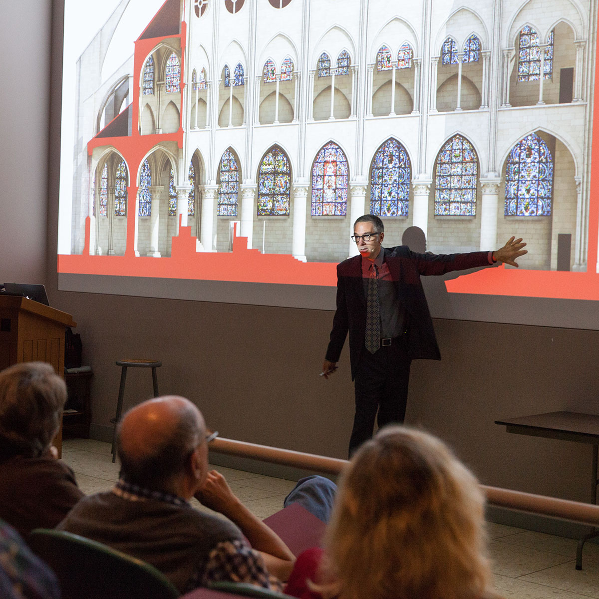 Person holding hand up to a screen showing an image of Notre-Dame de Paris stained glass windows.