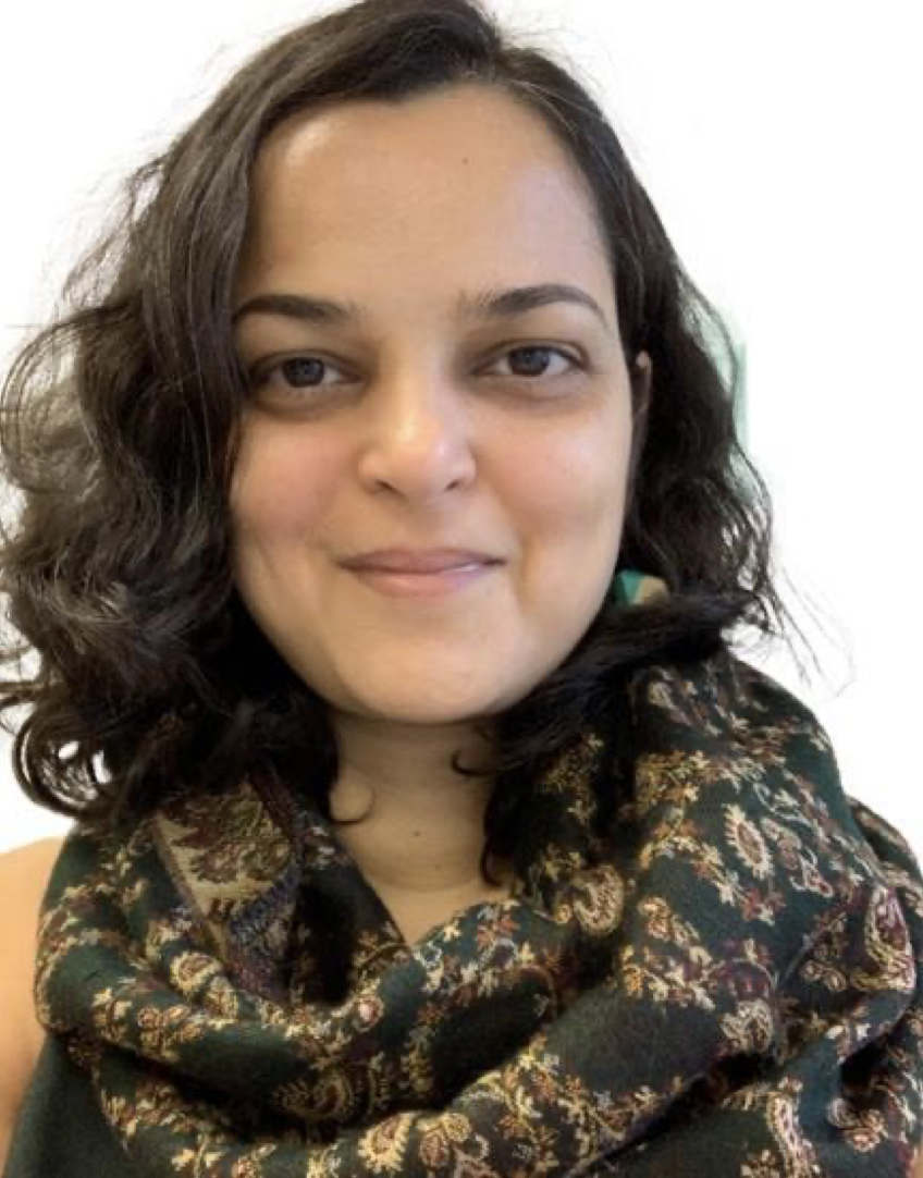 A person with long brown hair and a floral-patterned scarf smiles at the viewer.