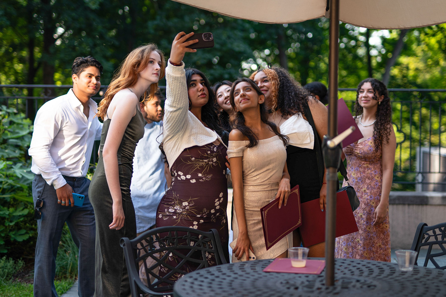A large group of people huddled together outside with one person holding up their phone for a group selfie.