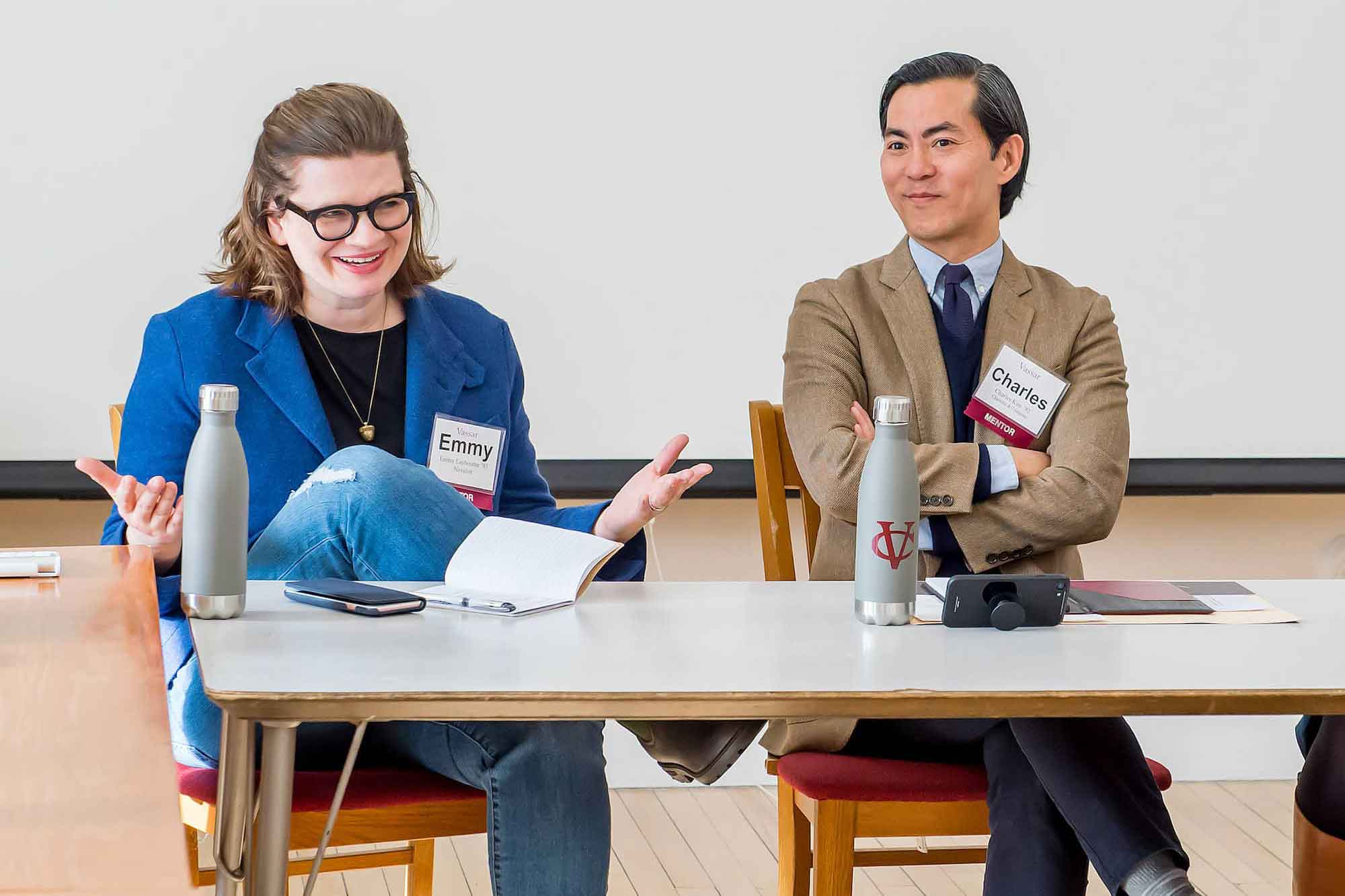 Two smiling people seated behind a table wearing name tags.