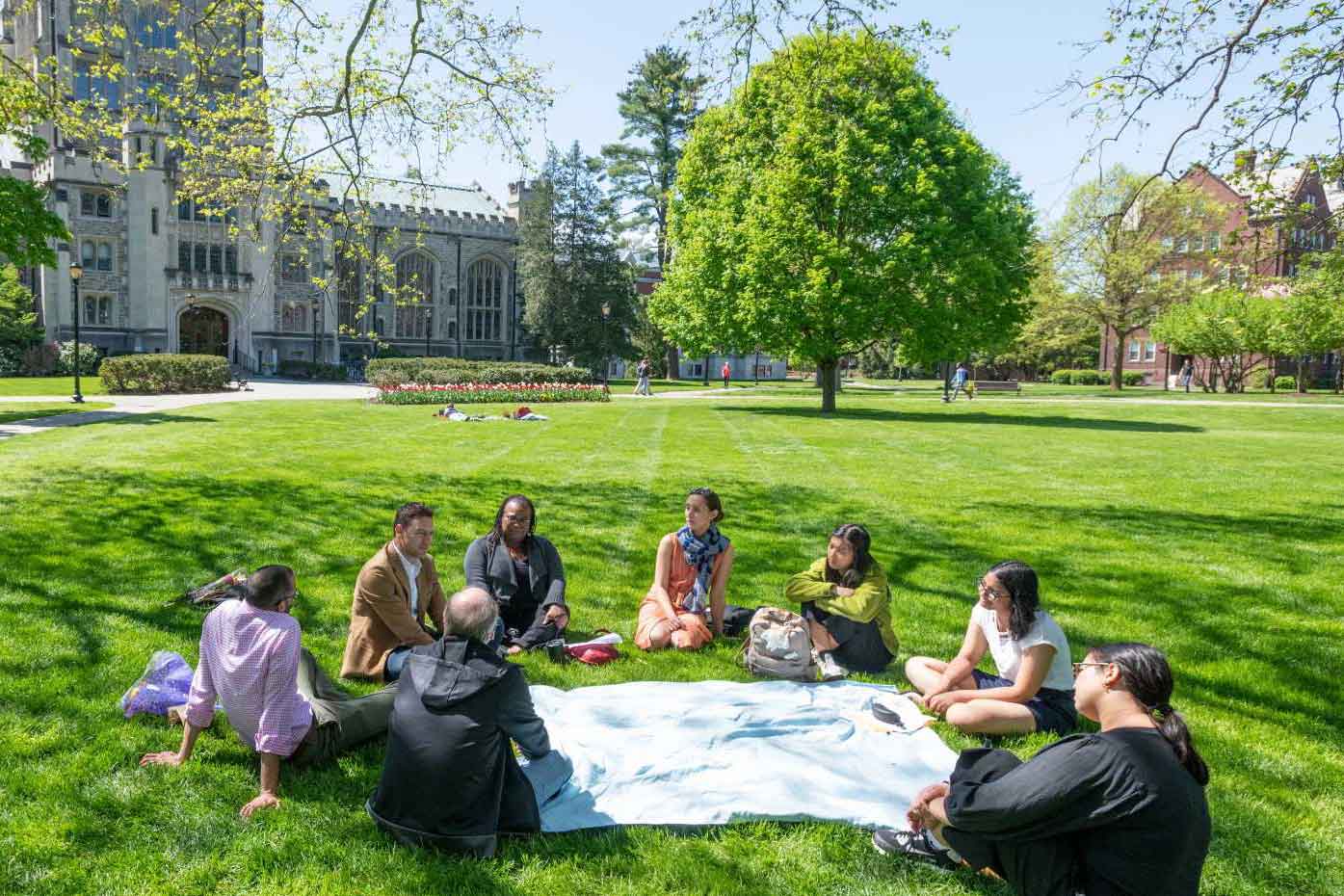 People seated in a circle on a lawn on Vassar campus.