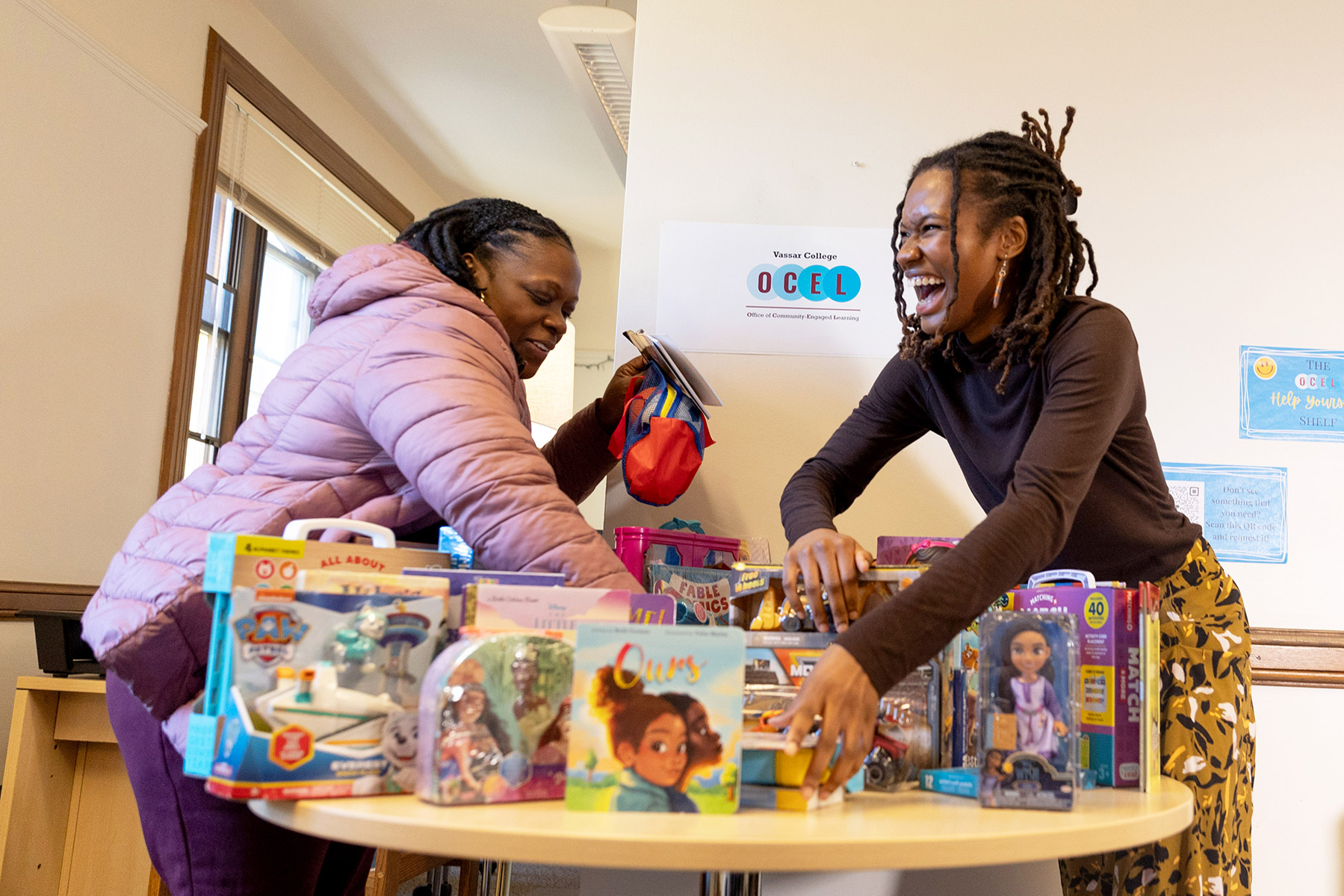 Two people standing in front a table filled with different boxes and presents.