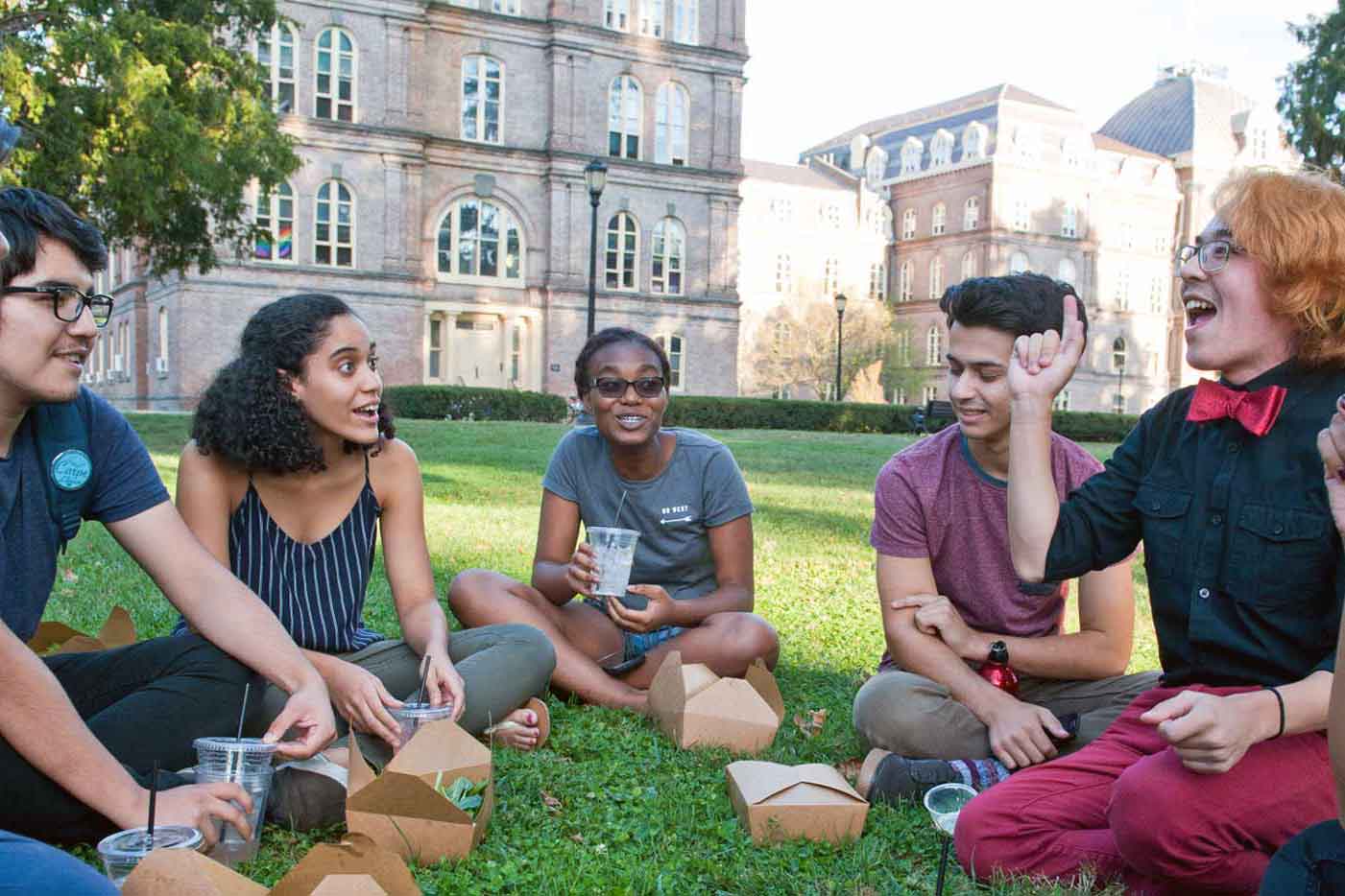 Group of smiling people sitting on a lawn on Vassar campus