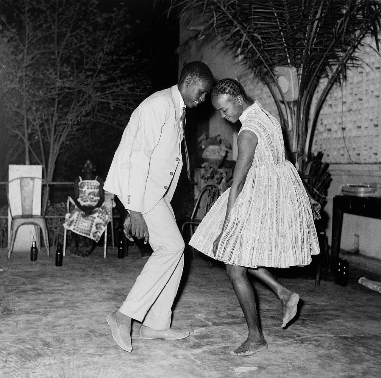 Black and white photo of two dancing people facing each other and smiling.