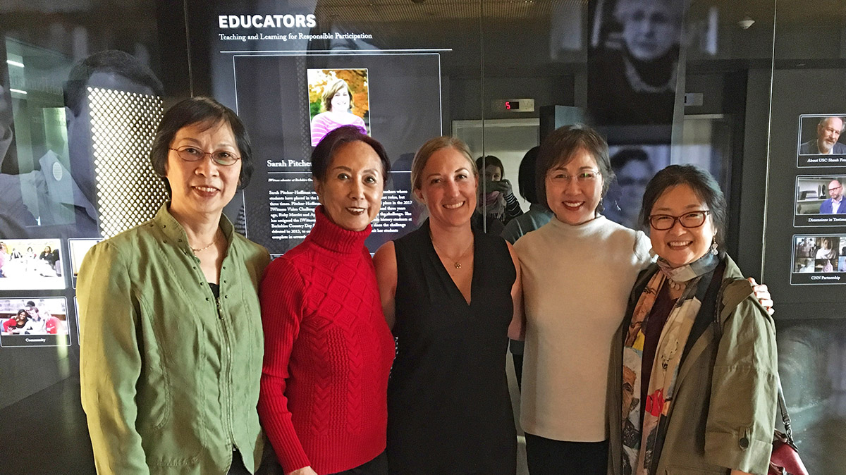 A group of five people standing in front of a glass display looking at the camera.