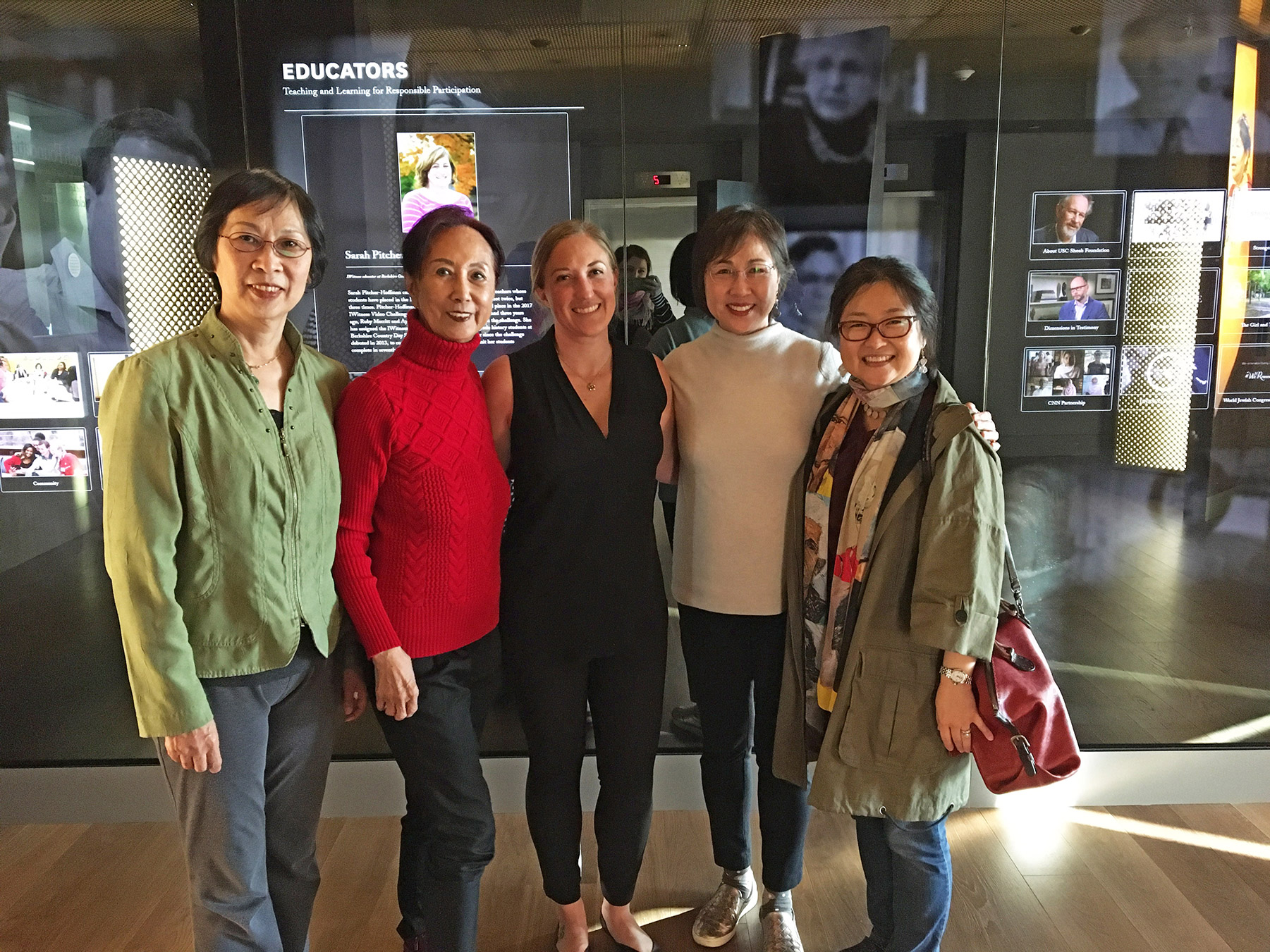 A group of five people standing in front of a glass display looking at the camera.